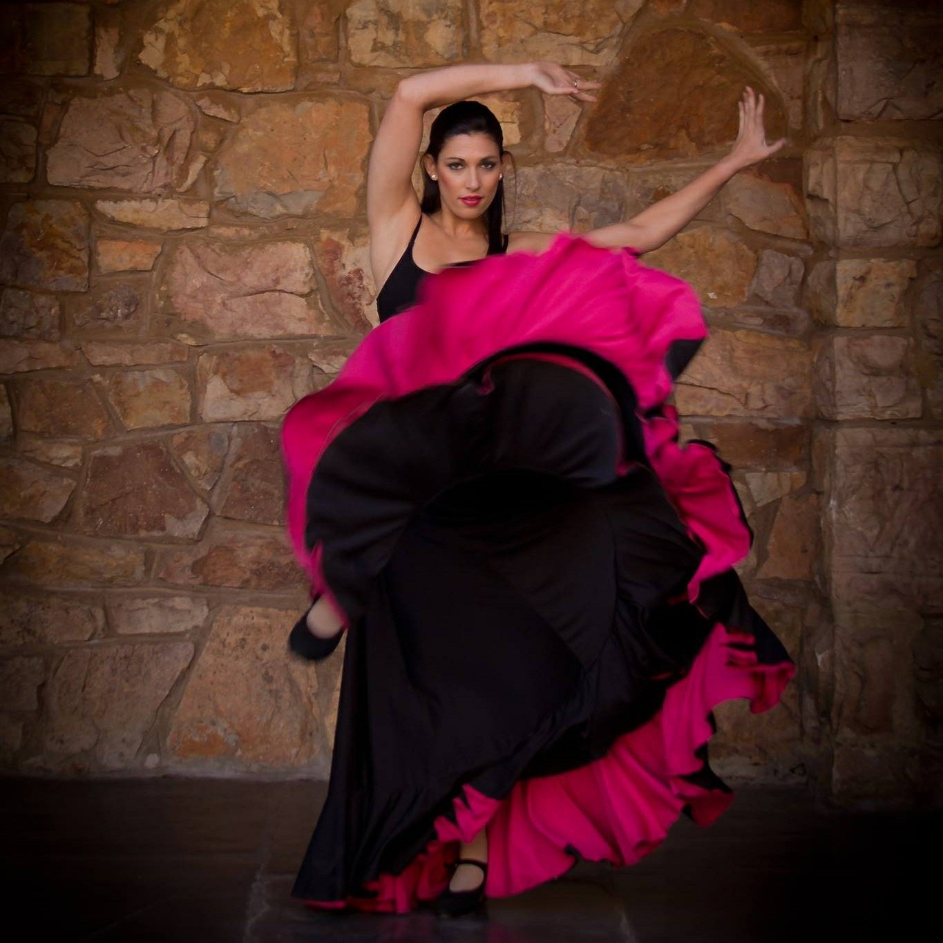 Nadia Katz performing a dramatic dance movement in a black and pink dress
